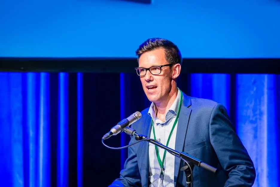 Troy Morgan speaking on stage at a conference