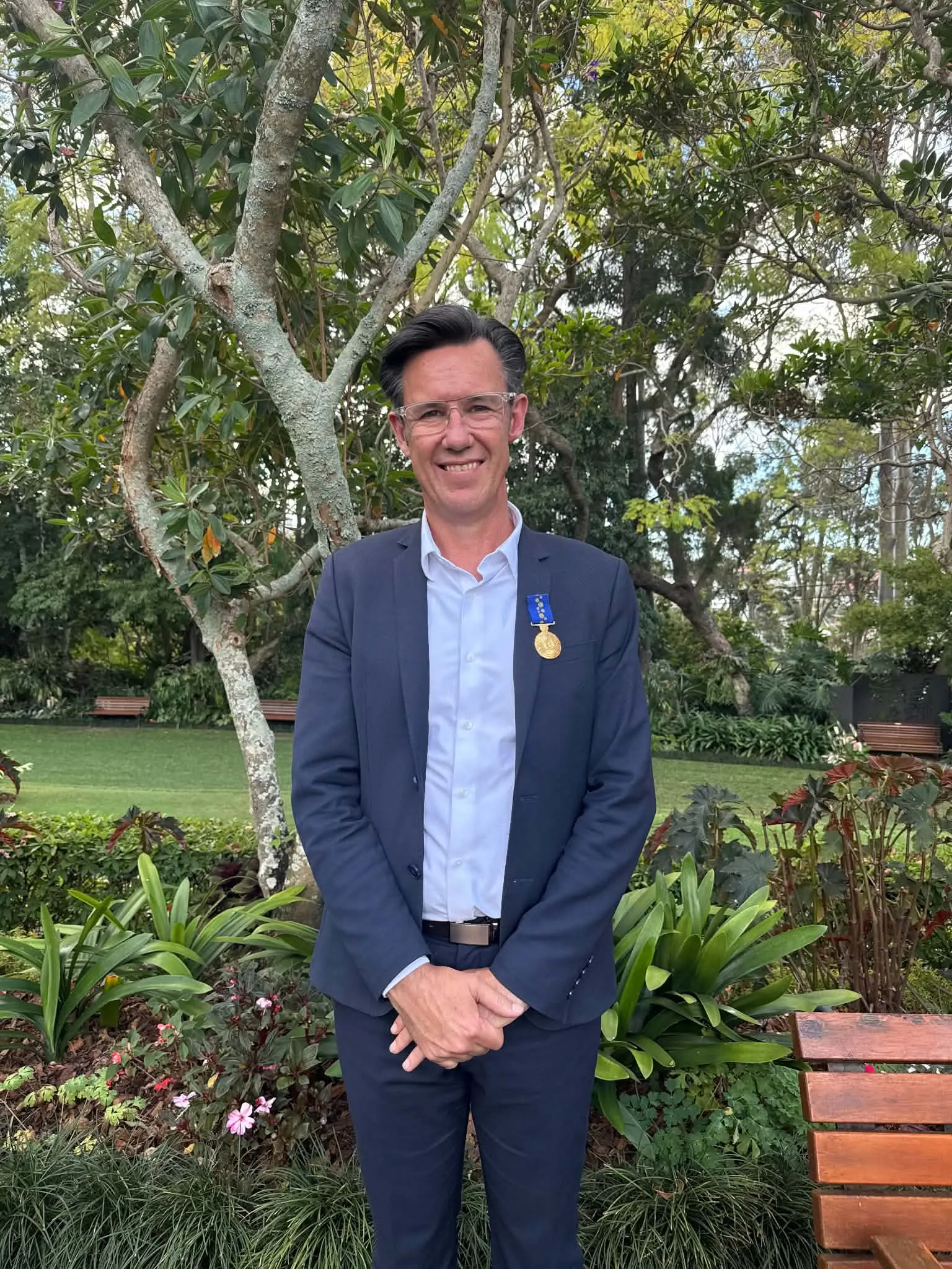Troy Morgan OAM wearing his Medal of the Order of Australia in a garden setting